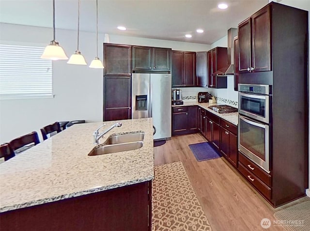 4218 SW Colbert Way, Port Orchard, WA 98367 - kitchen with appliances with stainless steel finishes, light wood finished floors, wall chimney exhaust hood, decorative light fixtures, and light stone countertops