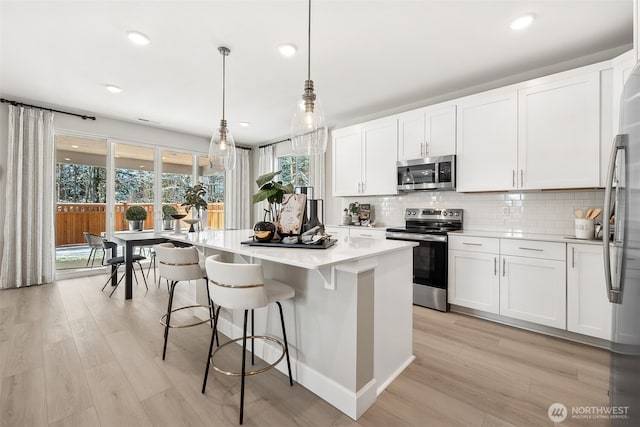 20230 150th St E Unit 598, Bonney Lake, WA 98391 - kitchen with stainless steel appliances, a kitchen island, backsplash, light wood finished floors, and light countertops