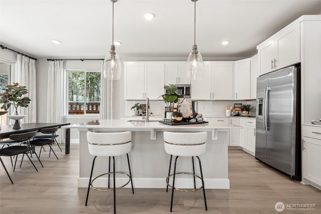 20230 150th St E Unit 598, Bonney Lake, WA 98391 - kitchen with appliances with stainless steel finishes, a kitchen bar, backsplash, light wood-style flooring, and recessed lighting