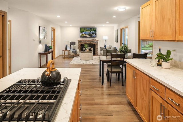 44422 SE 130th St, North Bend, WA 98045 - kitchen featuring a fireplace, stainless steel gas cooktop, light wood-style flooring, recessed lighting, and open floor plan