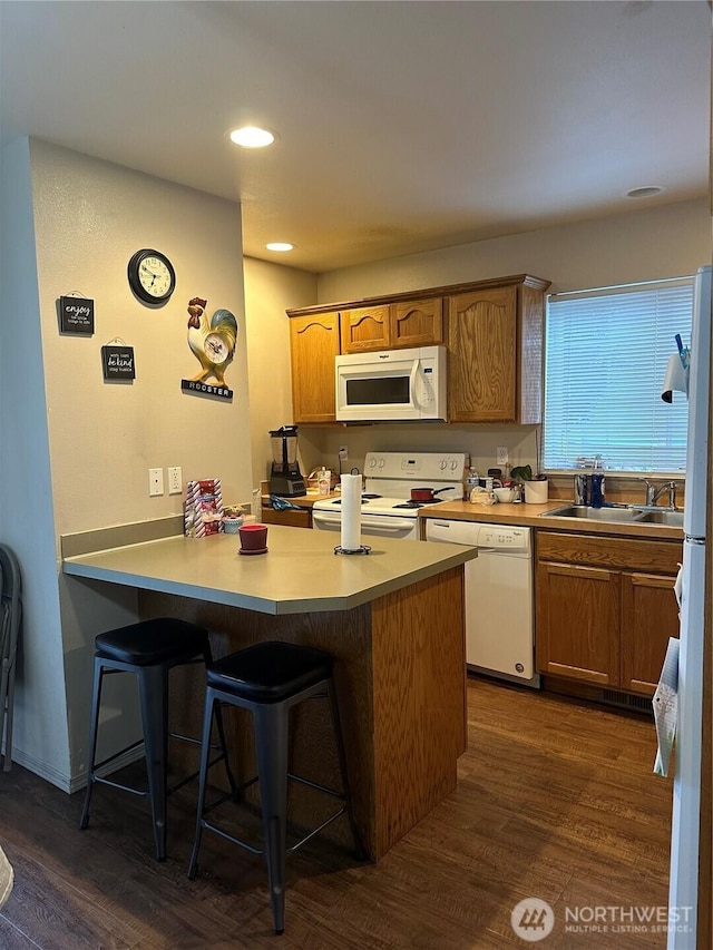 314 Birchwood Ln, Sedro Woolley, WA 98284 - kitchen with white appliances, a peninsula, dark wood-style flooring, a kitchen breakfast bar, and recessed lighting