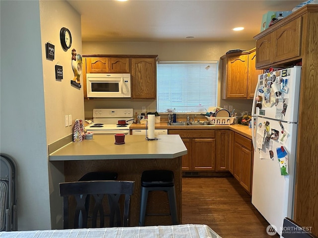 314 Birchwood Ln, Sedro Woolley, WA 98284 - kitchen featuring white appliances, a kitchen breakfast bar, a peninsula, light countertops, and dark wood-style flooring