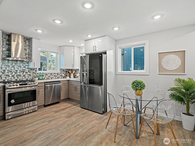 4853 42nd Ave SW, Seattle, WA 98116 - kitchen featuring appliances with stainless steel finishes, wall chimney exhaust hood, modern cabinets, tasteful backsplash, and light countertops