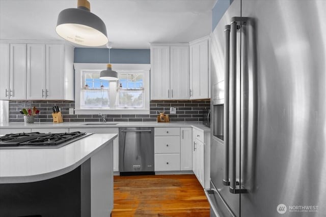 751 S 40th St, Tacoma, WA 98418 - kitchen featuring stainless steel appliances, decorative backsplash, white cabinetry, wood finished floors, and light countertops