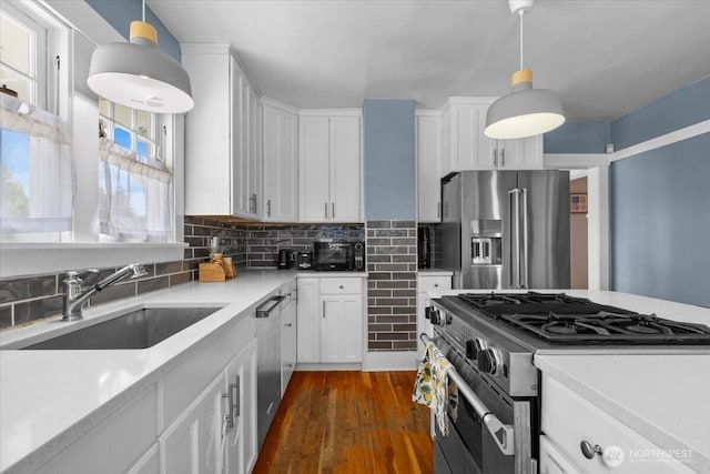 751 S 40th St, Tacoma, WA 98418 - kitchen featuring appliances with stainless steel finishes, light countertops, white cabinetry, dark wood-type flooring, and tasteful backsplash