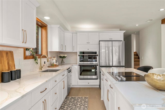 13710 41st Ave NE, Seattle, WA 98125 - kitchen with appliances with stainless steel finishes, white cabinets, light wood-style floors, tasteful backsplash, and recessed lighting