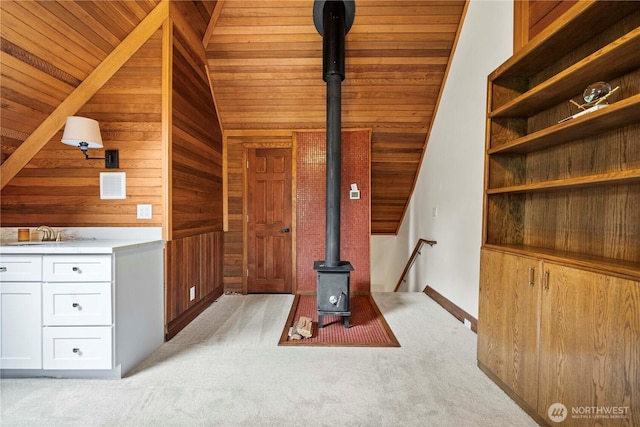 13710 41st Ave NE, Seattle, WA 98125 - unfurnished living room featuring lofted ceiling, a wood stove, light carpet, wood walls, and wood ceiling