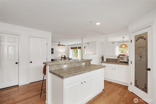 1344 Foreman Rd, Dupont, WA 98327 - kitchen featuring light wood finished floors, a kitchen breakfast bar, white cabinets, ceiling fan, and recessed lighting