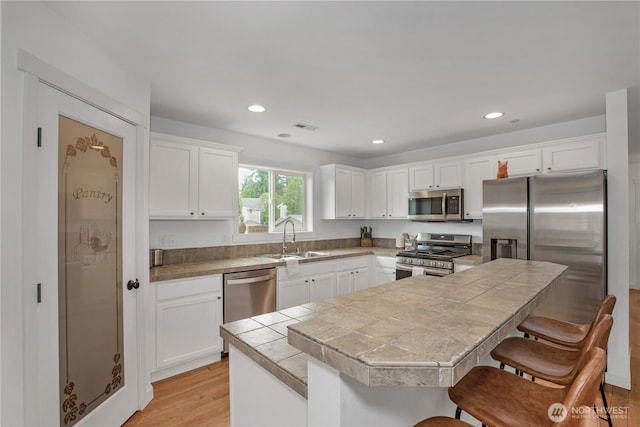 1344 Foreman Rd, Dupont, WA 98327 - kitchen featuring appliances with stainless steel finishes, a kitchen bar, white cabinets, recessed lighting, and light wood-style flooring