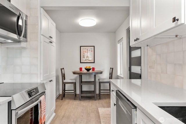 102 NW 132nd St, Seattle, WA 98177 - kitchen featuring appliances with stainless steel finishes, light countertops, light wood-style floors, and white cabinetry