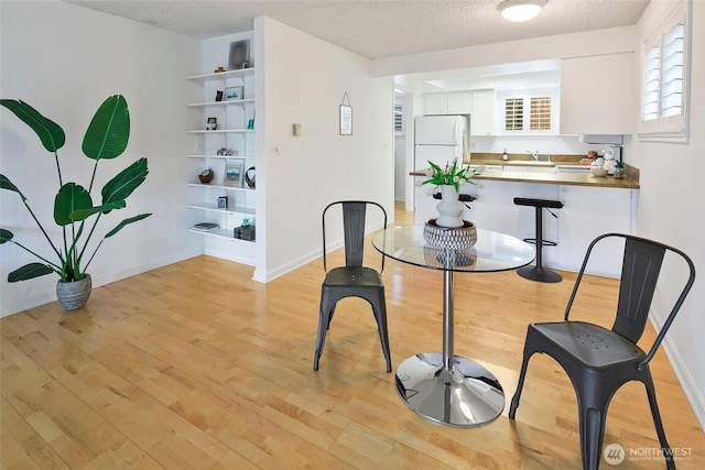 4444 44th Ave SW Unit 101, Seattle, WA 98116 - dining area featuring light wood-type flooring and a textured ceiling