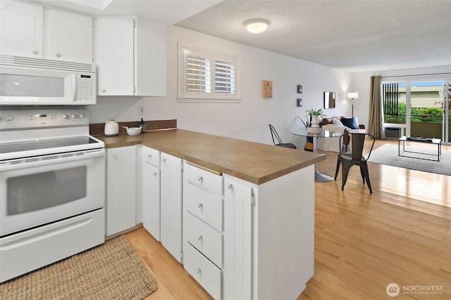 4444 44th Ave SW Unit 101, Seattle, WA 98116 - kitchen with white appliances, a peninsula, open floor plan, white cabinetry, and light wood-style flooring