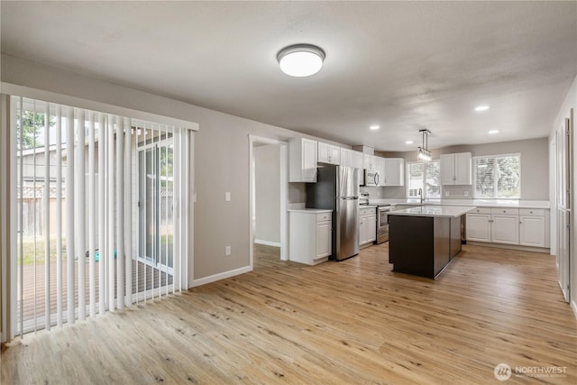 1513 154th St E, Tacoma, WA 98445 - kitchen with appliances with stainless steel finishes, light wood finished floors, light countertops, a kitchen island, and white cabinetry