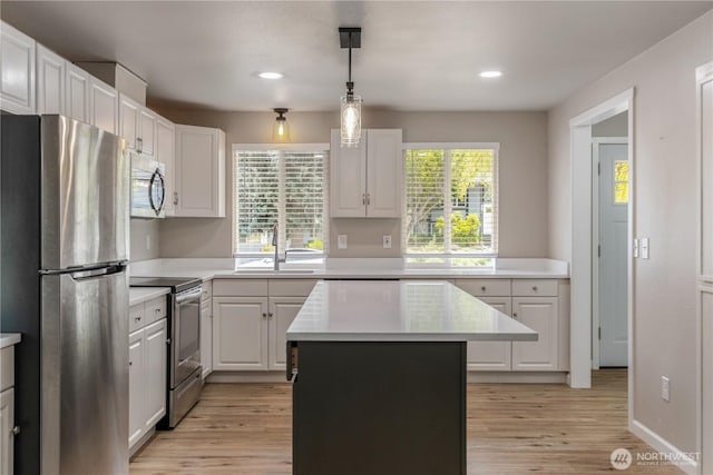 1513 154th St E, Tacoma, WA 98445 - kitchen featuring stainless steel appliances, light countertops, light wood finished floors, a center island, and white cabinets