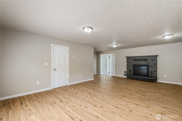 1513 154th St E, Tacoma, WA 98445 - unfurnished living room with light wood-style flooring, a textured ceiling, and a brick fireplace