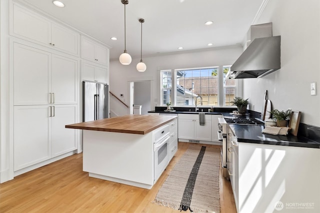1615 Monroe St, Bellingham, WA 98225 - kitchen featuring wall chimney range hood, wooden counters, white cabinetry, light wood-style floors, and white oven