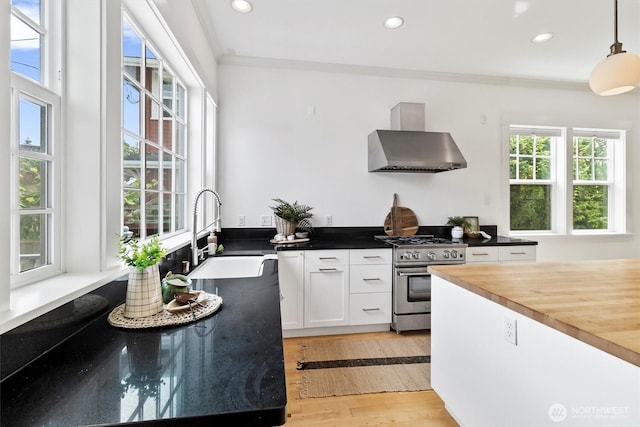 1615 Monroe St, Bellingham, WA 98225 - kitchen featuring wall chimney range hood, stainless steel gas range oven, ornamental molding, wood counters, and white cabinets