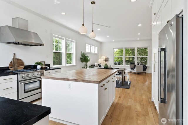 1615 Monroe St, Bellingham, WA 98225 - kitchen featuring appliances with stainless steel finishes, wall chimney exhaust hood, wooden counters, white cabinetry, and recessed lighting