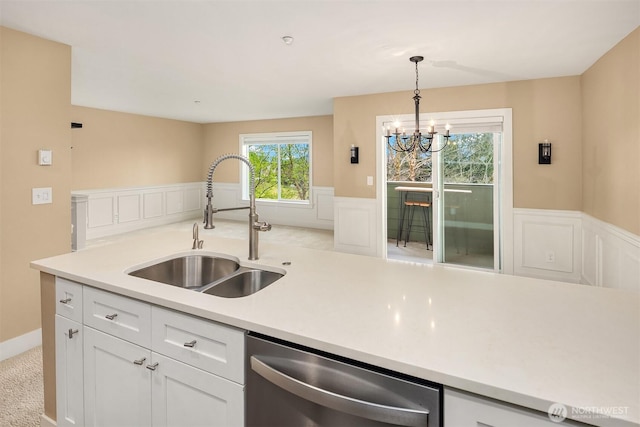 1957 23rd Pl NE Unit 201, Issaquah, WA 98029 - kitchen with stainless steel dishwasher, light countertops, a wainscoted wall, a chandelier, and white cabinetry