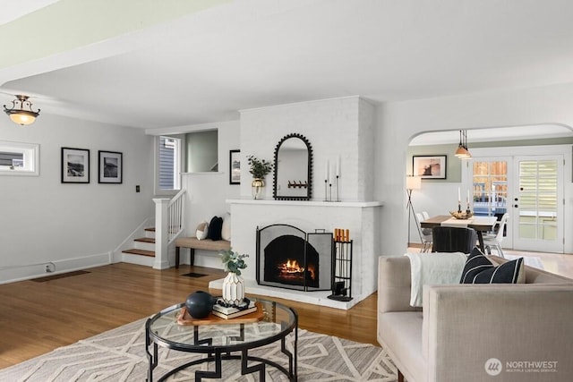4055 SW Prince St, Seattle, WA 98116 - living room featuring wood finished floors, a brick fireplace, and stairway