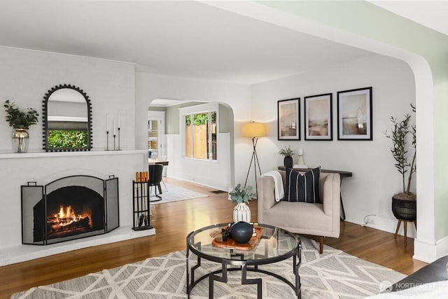 4055 SW Prince St, Seattle, WA 98116 - living room featuring arched walkways, wood finished floors, and a brick fireplace