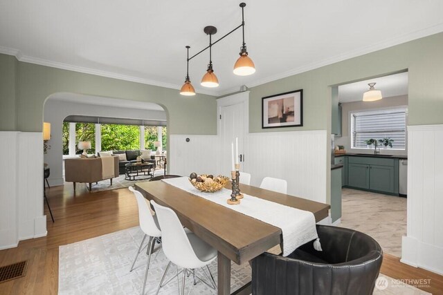 4055 SW Prince St, Seattle, WA 98116 - dining space with arched walkways, wainscoting, crown molding, and light wood finished floors