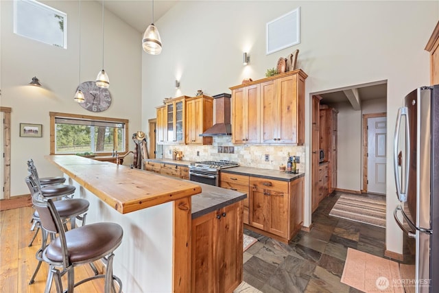 95 Horizon Ln, Chelan, WA 98816 - kitchen with stainless steel appliances, wall chimney range hood, a towering ceiling, wood counters, and backsplash