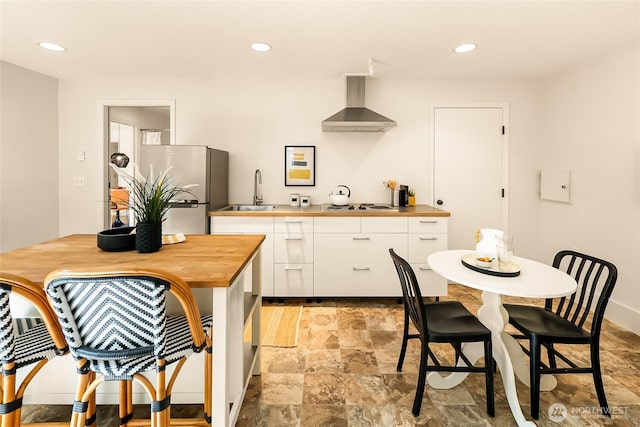 2325 38th Ave E, Seattle, WA 98112 - kitchen with wall chimney range hood, freestanding refrigerator, wooden counters, white cabinetry, and white stovetop