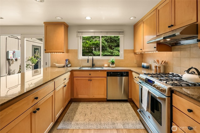 2325 38th Ave E, Seattle, WA 98112 - kitchen featuring appliances with stainless steel finishes, under cabinet range hood, light stone countertops, backsplash, and light wood finished floors
