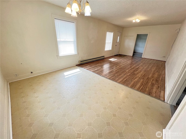 552 Maple St S, Okanogan, WA 98844 - empty room with a baseboard radiator, a chandelier, and a textured ceiling