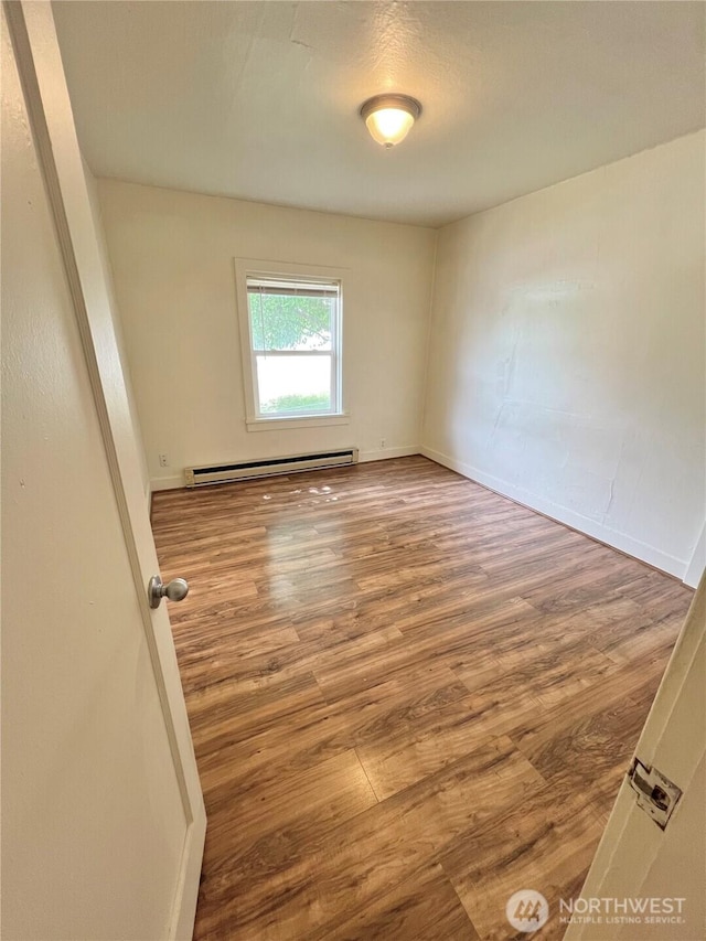 552 Maple St S, Okanogan, WA 98844 - empty room featuring a baseboard heating unit and wood finished floors