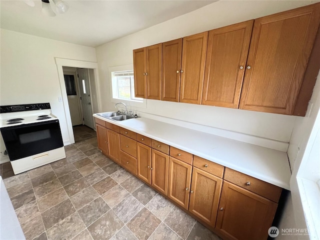 552 Maple St S, Okanogan, WA 98844 - kitchen with white range with electric cooktop, brown cabinetry, stone finish floors, and light countertops