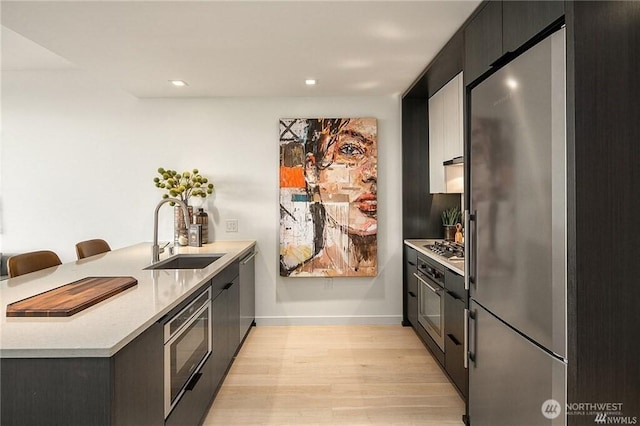 590 1st Ave S Unit 907, Seattle, WA 98104 - kitchen with stainless steel appliances, a peninsula, light wood-style flooring, light countertops, and modern cabinets