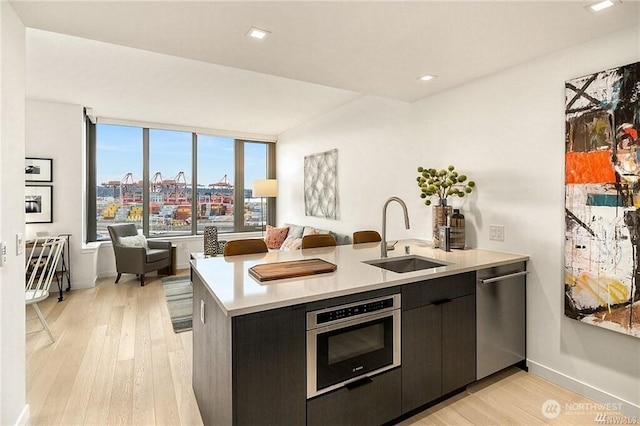 590 1st Ave S Unit 907, Seattle, WA 98104 - kitchen with stainless steel appliances, light countertops, open floor plan, light wood finished floors, and dark cabinetry