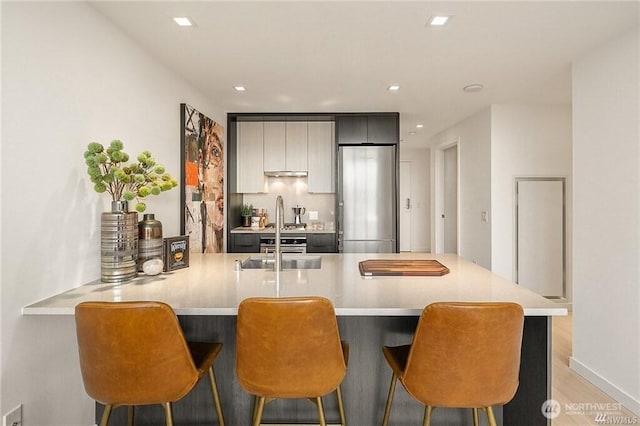 590 1st Ave S Unit 907, Seattle, WA 98104 - kitchen with stainless steel refrigerator, light countertops, light wood-type flooring, a peninsula, and recessed lighting