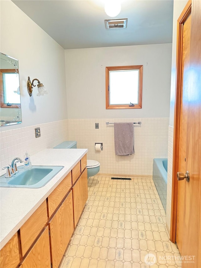 16 W Douglas St, Harrington, WA 99134 - bathroom featuring tile walls, vanity, wainscoting, a bathtub, and tile patterned floors