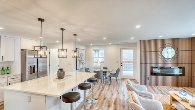 840 SW 306th St, Federal Way, WA 98023 - kitchen with stainless steel fridge, white cabinetry, a kitchen island, light wood-type flooring, and a breakfast bar area