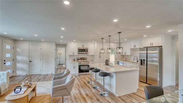 840 SW 306th St, Federal Way, WA 98023 - kitchen featuring stainless steel appliances, light wood finished floors, a breakfast bar, white cabinetry, and recessed lighting