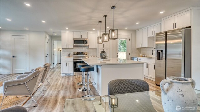 840 SW 306th St, Federal Way, WA 98023 - kitchen featuring stainless steel appliances, light wood-type flooring, white cabinets, light countertops, and decorative backsplash