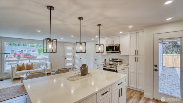 840 SW 306th St, Federal Way, WA 98023 - kitchen with appliances with stainless steel finishes, white cabinetry, light wood-style flooring, tasteful backsplash, and recessed lighting