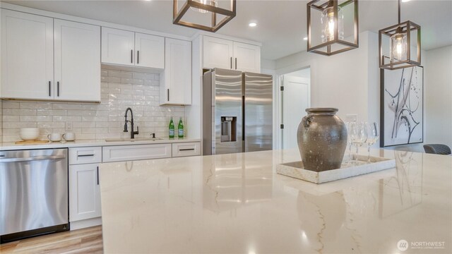 840 SW 306th St, Federal Way, WA 98023 - kitchen featuring stainless steel appliances, backsplash, white cabinets, light stone counters, and decorative light fixtures