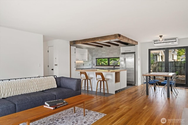6024 Gould Ave S, Seattle, WA 98108 - living area featuring light wood-style flooring, beam ceiling, and an AC wall unit