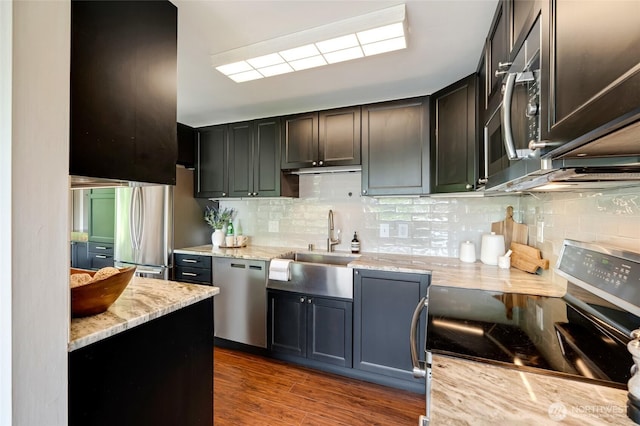 1110 E Harrison St Unit 301, Seattle, WA 98102 - kitchen featuring appliances with stainless steel finishes, backsplash, light stone countertops, and wood finished floors