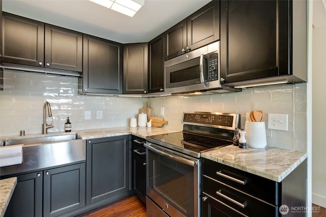 1110 E Harrison St Unit 301, Seattle, WA 98102 - kitchen featuring appliances with stainless steel finishes, decorative backsplash, dark wood-style flooring, and light stone countertops