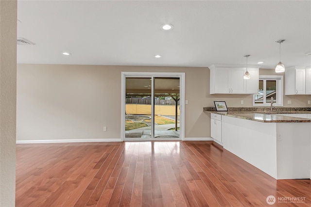 3005 Old Morse Rd SE, Olympia, WA 98501 - kitchen with dark stone countertops, white cabinets, light wood-style floors, recessed lighting, and hanging light fixtures