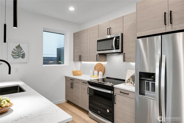 629A W Emerson Ave, Seattle, WA 98119 - kitchen featuring appliances with stainless steel finishes, backsplash, light wood finished floors, light stone countertops, and recessed lighting