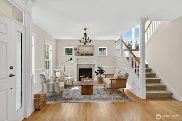 2414 42nd Pl, Anacortes, WA 98221 - living room with stairs, light wood-style flooring, a fireplace, a chandelier, and wainscoting
