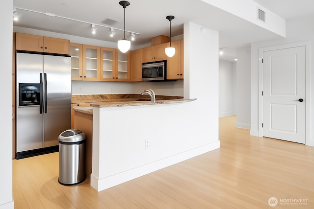 745 Bellevue Ave E Unit 109, Seattle, WA 98102 - kitchen with stainless steel appliances, light wood-type flooring, glass insert cabinets, hanging light fixtures, and a peninsula