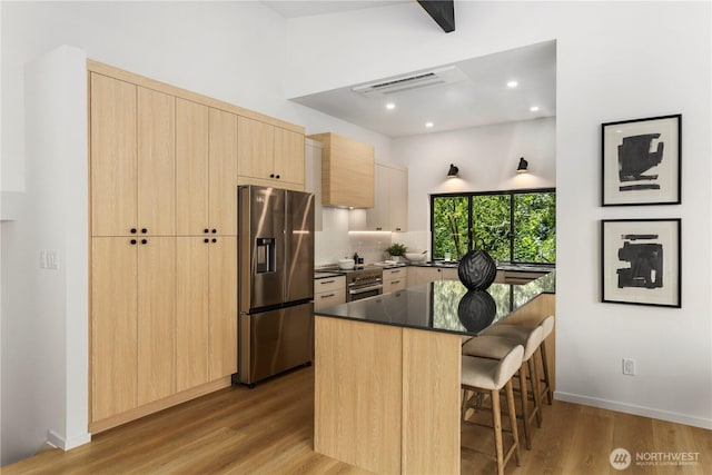 11029 84th Ave S, Seattle, WA 98178 - kitchen featuring stainless steel appliances, light brown cabinetry, a kitchen bar, wood finished floors, and decorative backsplash