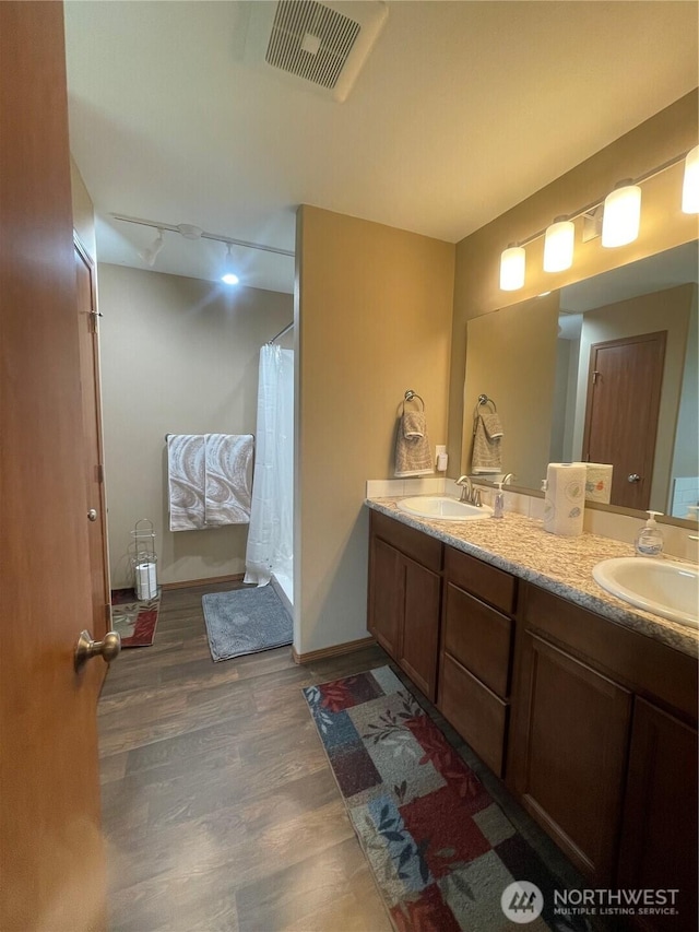 1717 Krause Rd, Raymond, WA 98577 - full bath featuring double vanity, wood finished floors, rail lighting, and a shower with shower curtain